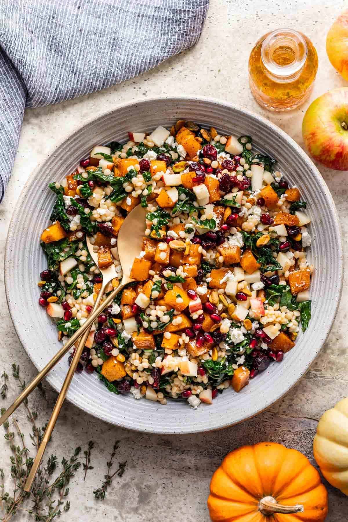 Pumpkin couscous salad in a large serving bowl with serving spoons.