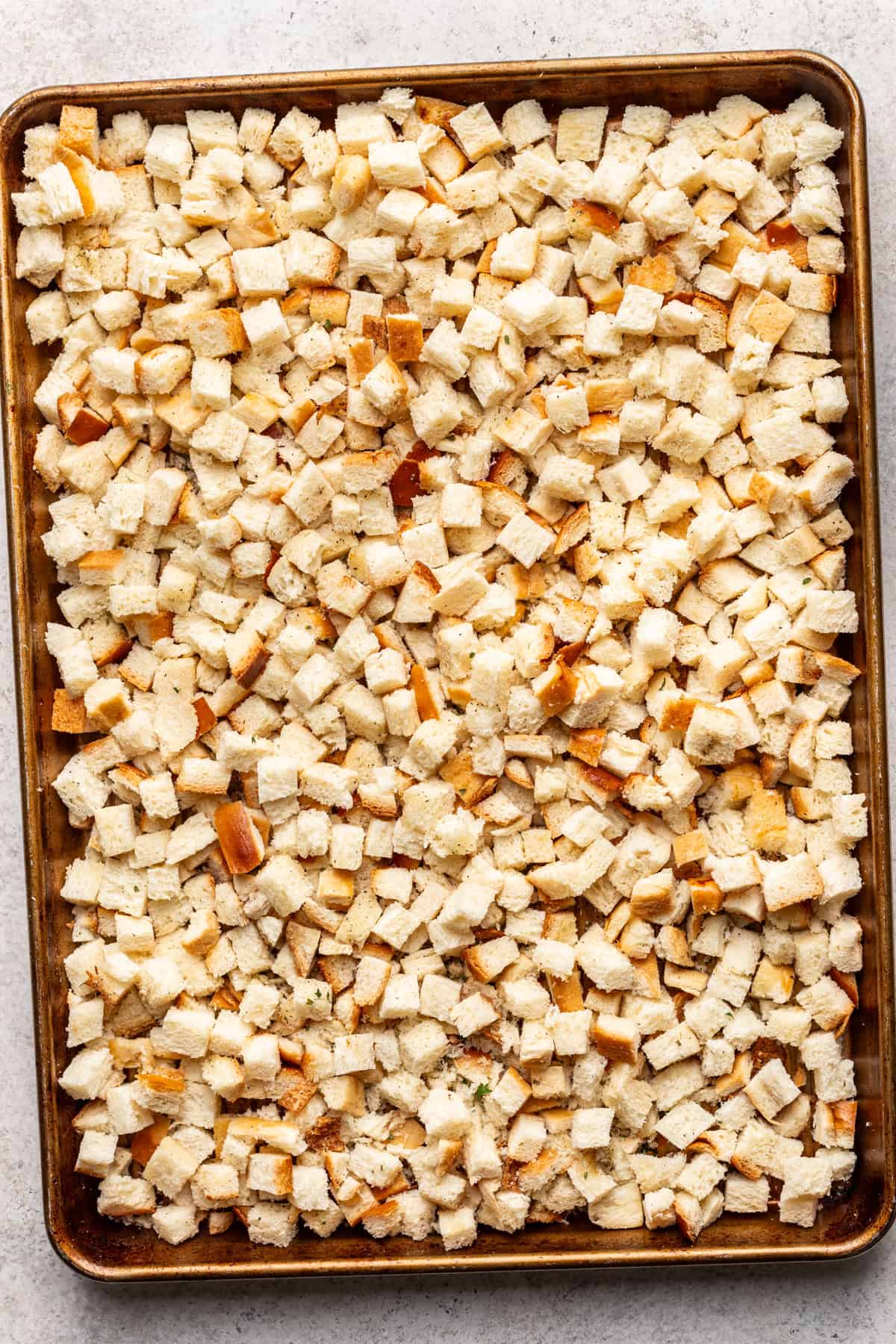 Seasoned diced challah on a large baking sheet.