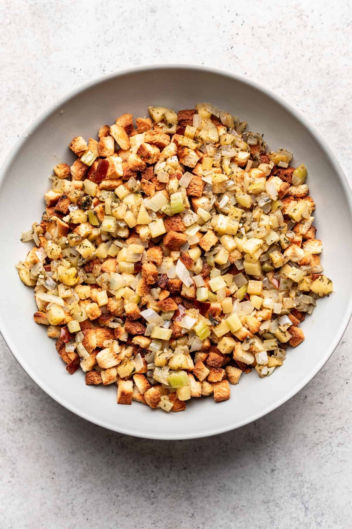 Toasted challah, softened vegetables, and egg/broth mixture combined in a mixing bowl.