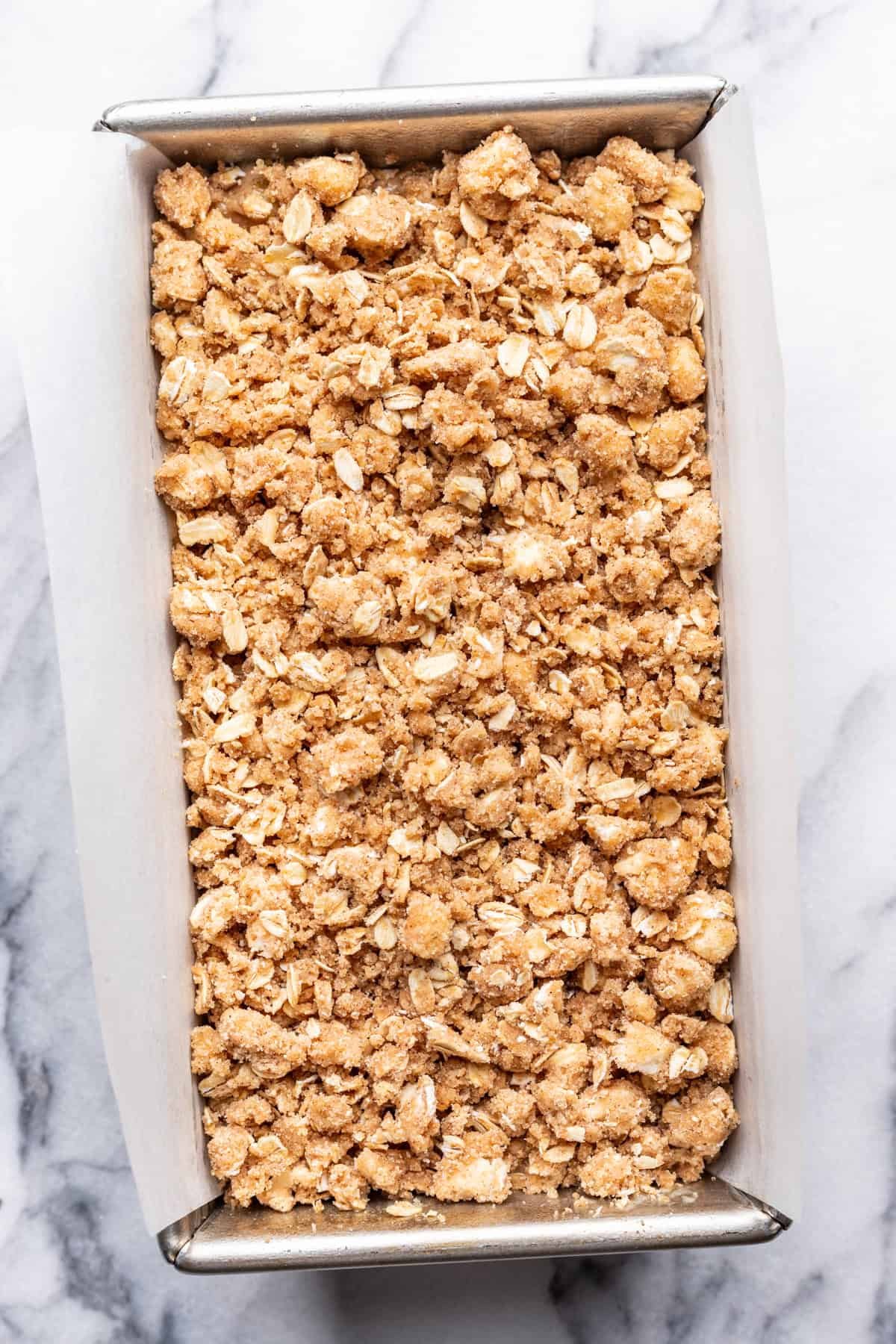 Raw batter and oat crumble in a loaf pan.