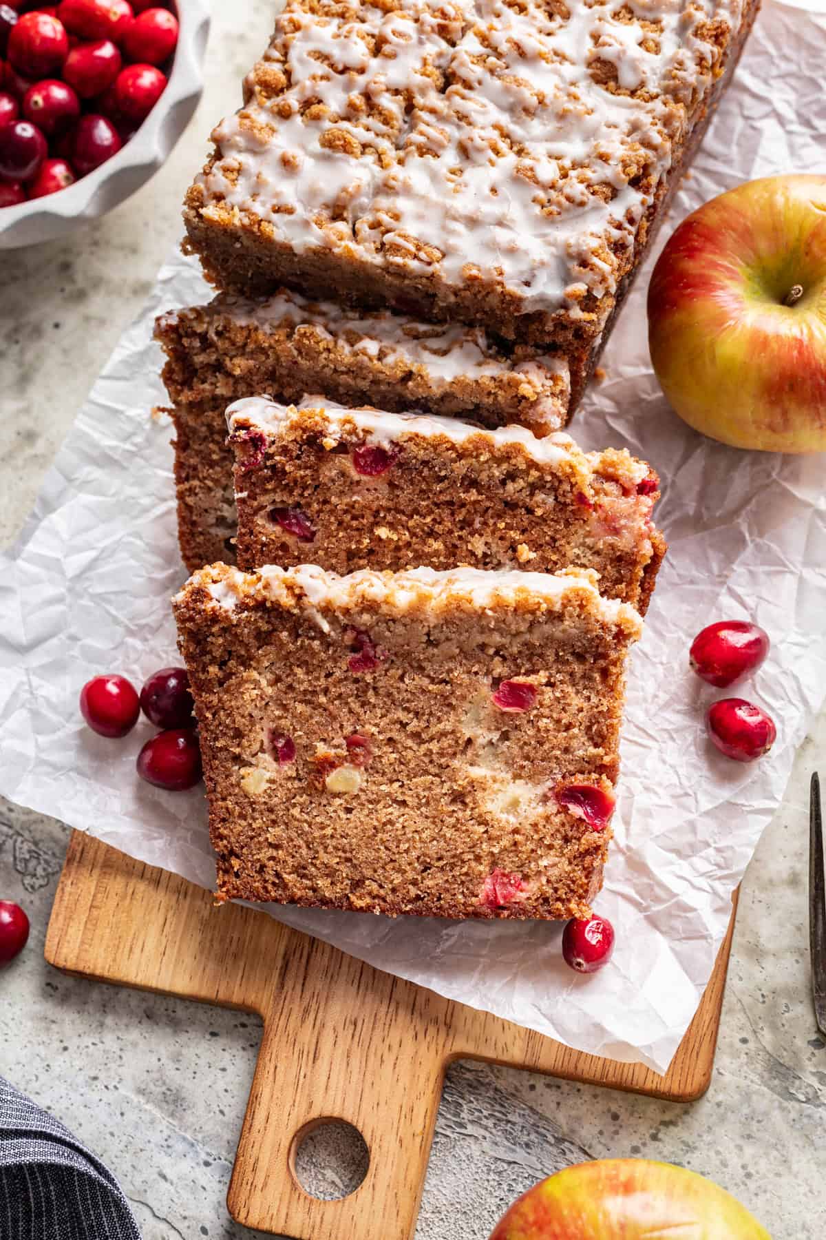 Sliced cranberry apple bread on a wood serving board.
