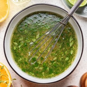 Citrus herb balsamic vinaigrette in a mixing bowl with a whisk.