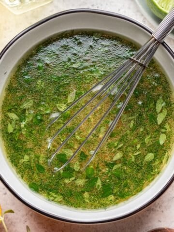 Citrus herb balsamic vinaigrette in a mixing bowl with a whisk.