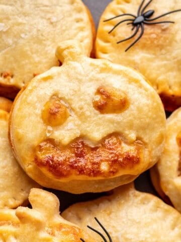Jack o Lantern Pizza Rolls stacked on a plate.