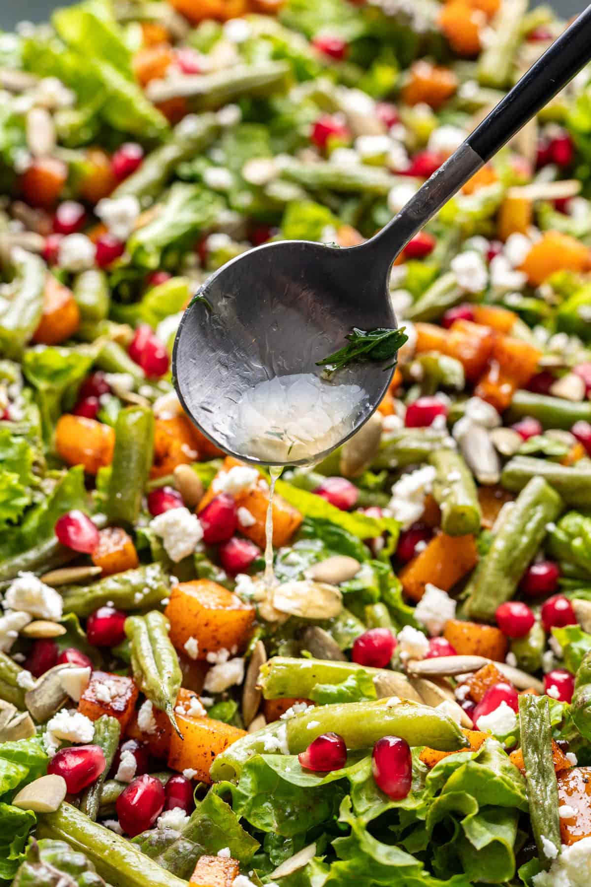 Drizzling citrus herb salad dressing over a salad.