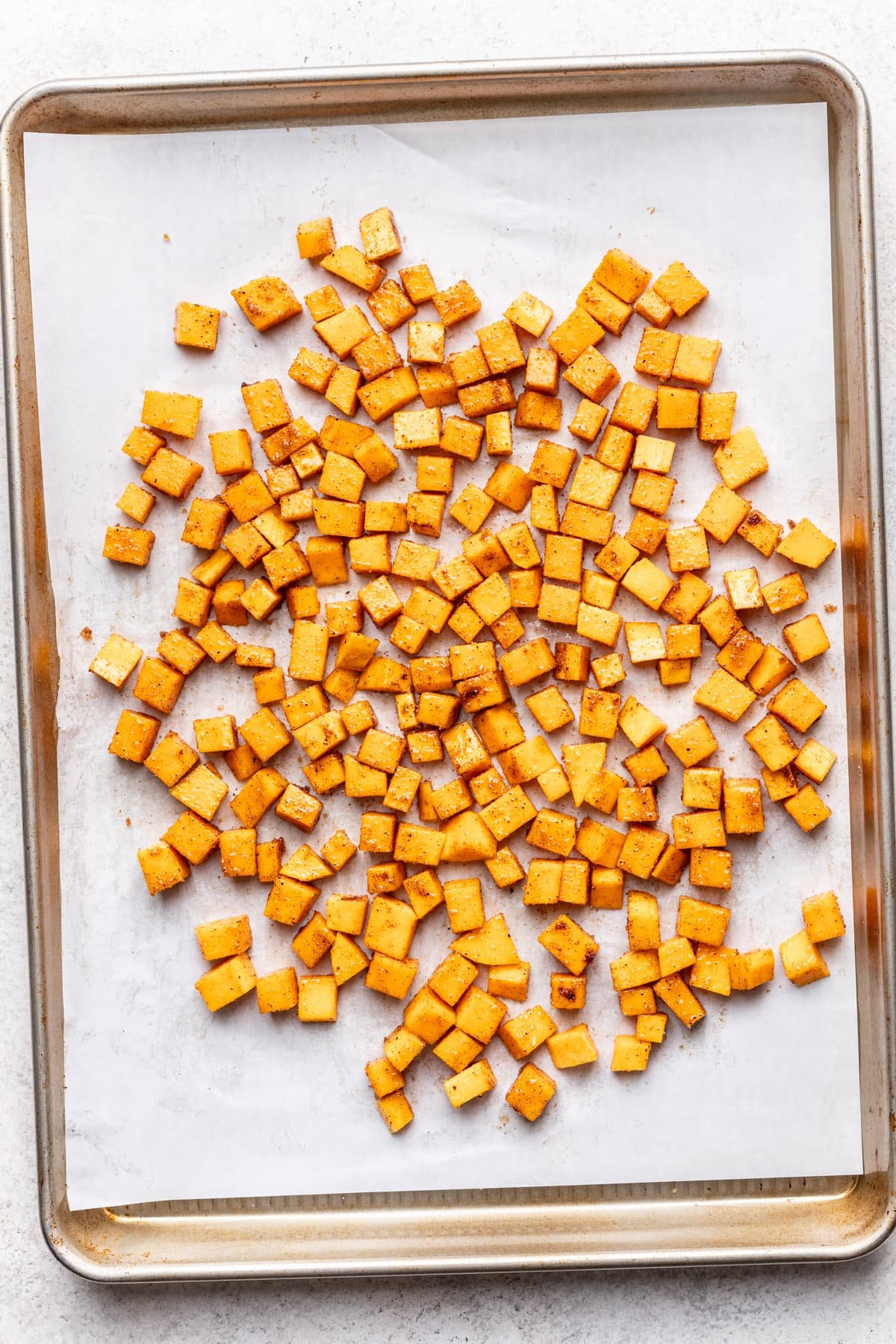 Cubed butternut squash on a baking sheet.