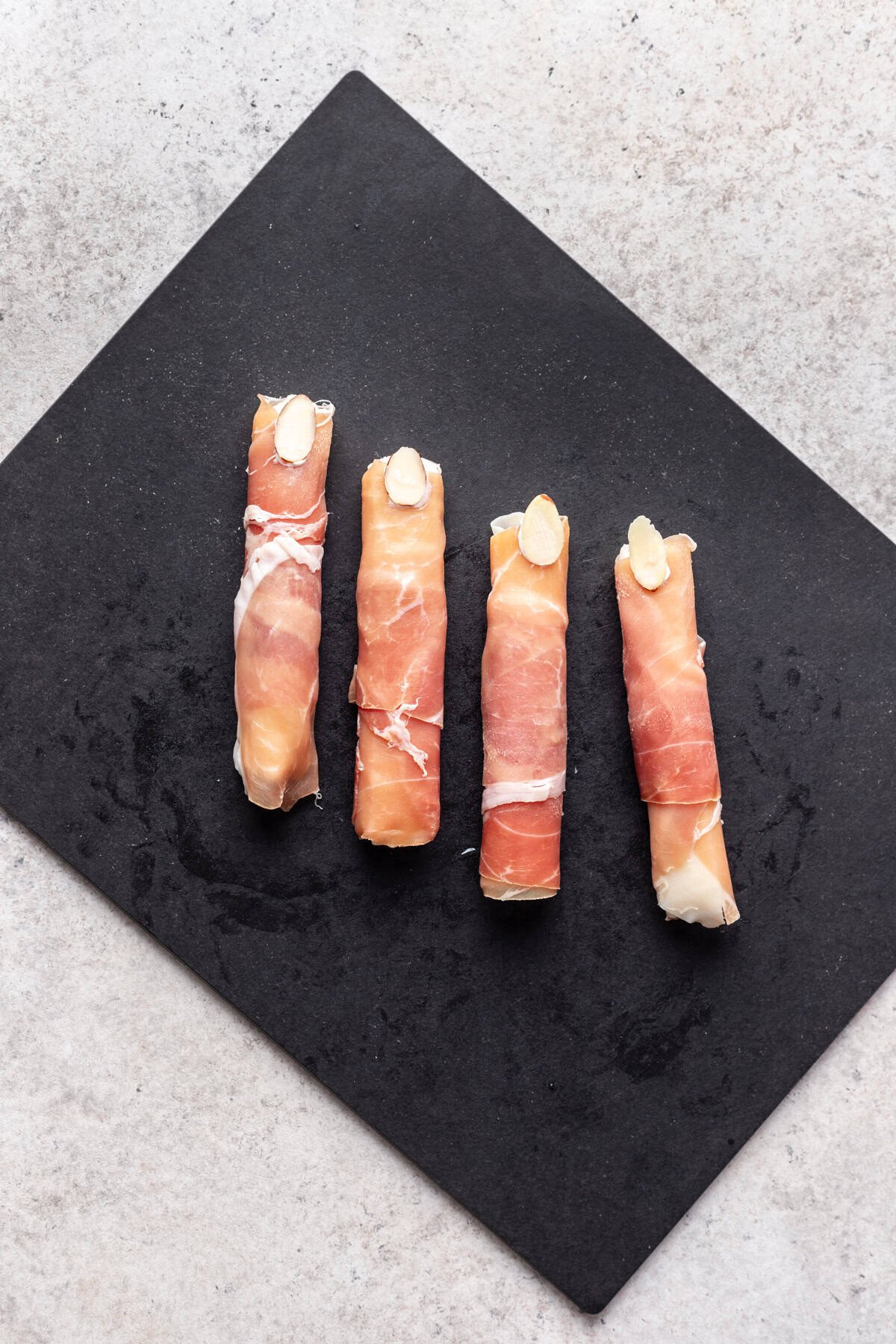 Cheesesticks wrapped in prosciutto with an almond on top to look like a finger nail.