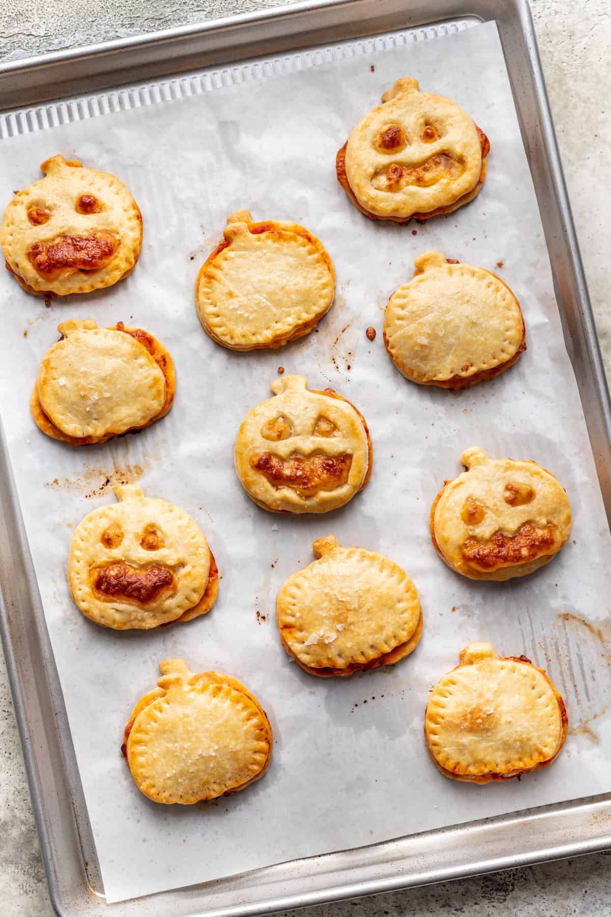 Baked jack o lantern pizza rolls on a baking sheet.