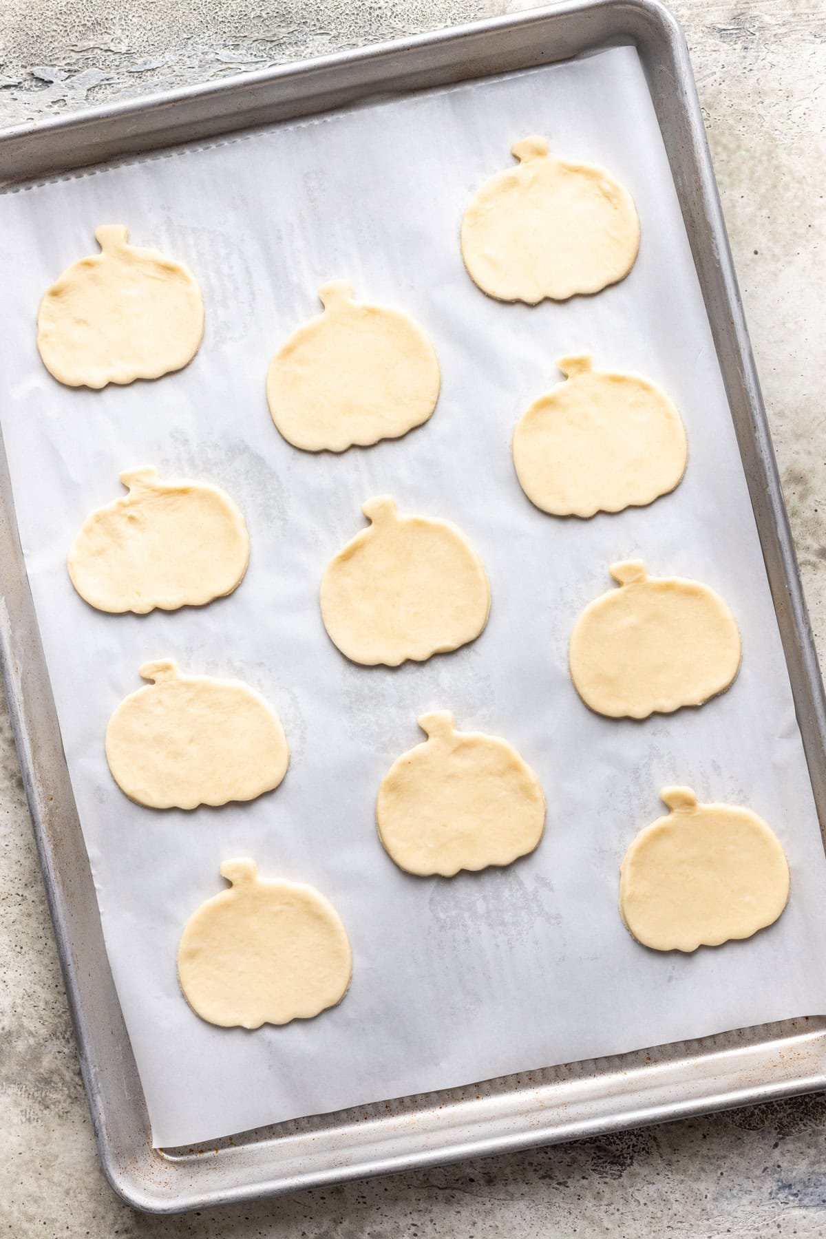 Pizza shapes cut out of the pizza roll dough and placed on a baking sheet.