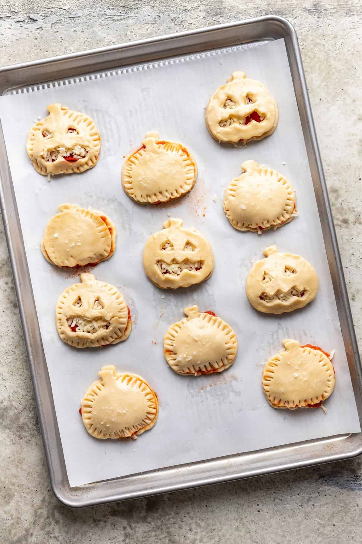 Jack o lantern pizza rolls on a baking sheet before baking.