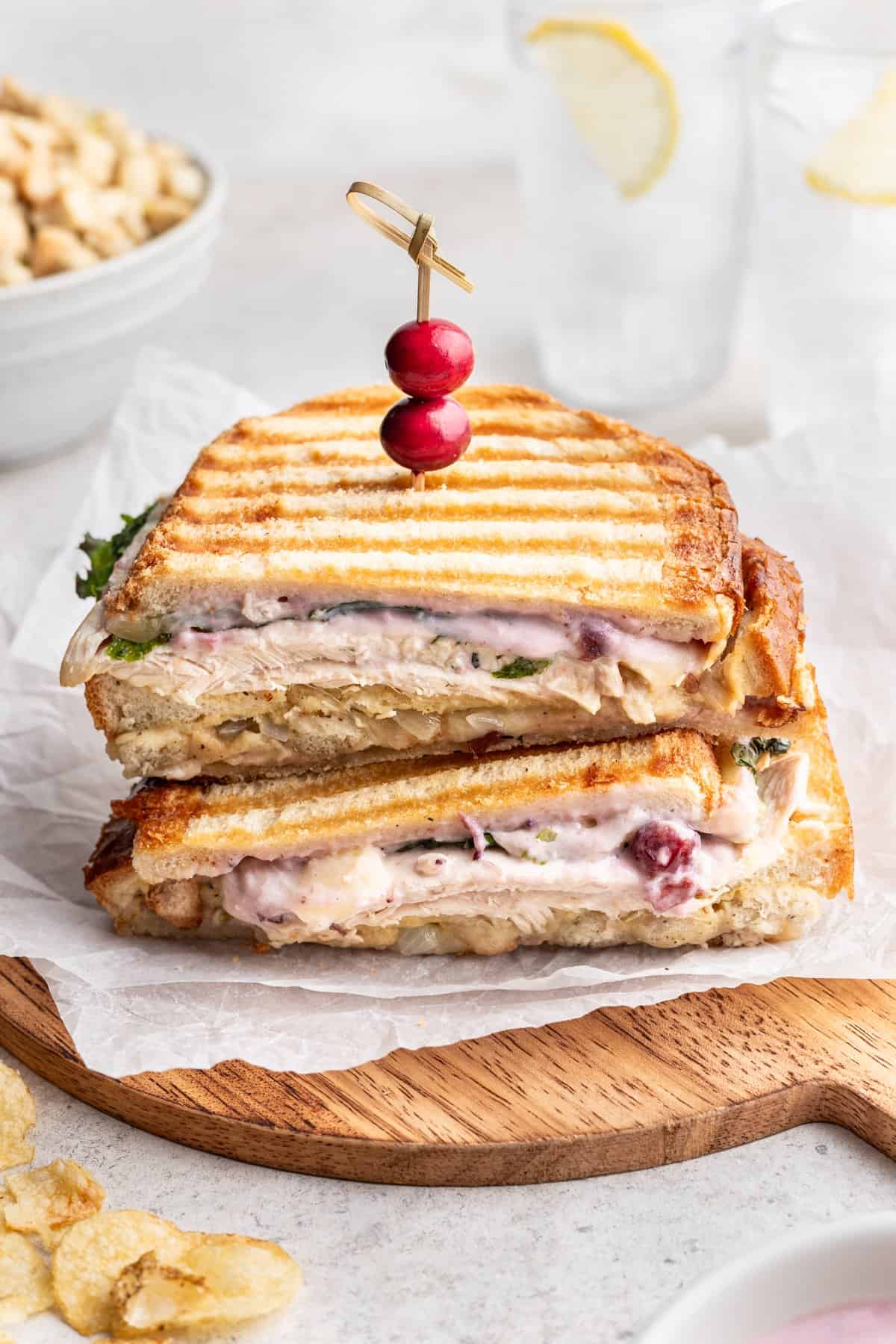 A leftover thanksgiving panini filled with thanksgiving leftovers and topped with a cranberry toothpick.