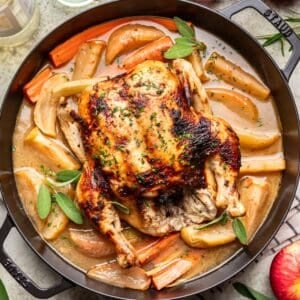 Roasted Thanksgiving Chicken in a large skillet with gravy, carrots, and baked apples.