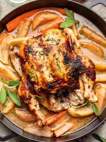 Roasted Thanksgiving Chicken in a large skillet with gravy, carrots, and baked apples.
