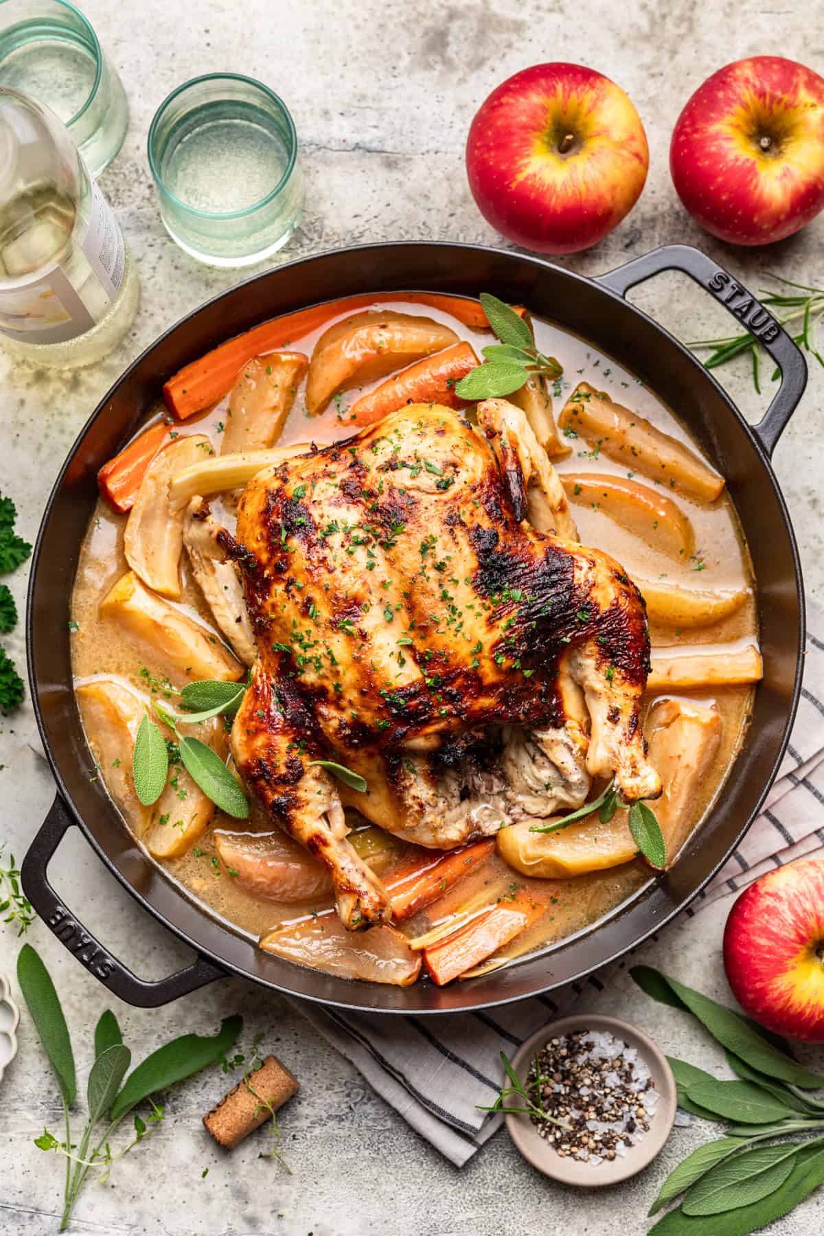 Roasted Thanksgiving Chicken in a large roasting pan with a cider gravy, baked apples, and cooked carrots.