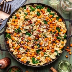 Roasted butternut squash pasta with ground chicken and kale in a large black skillet.