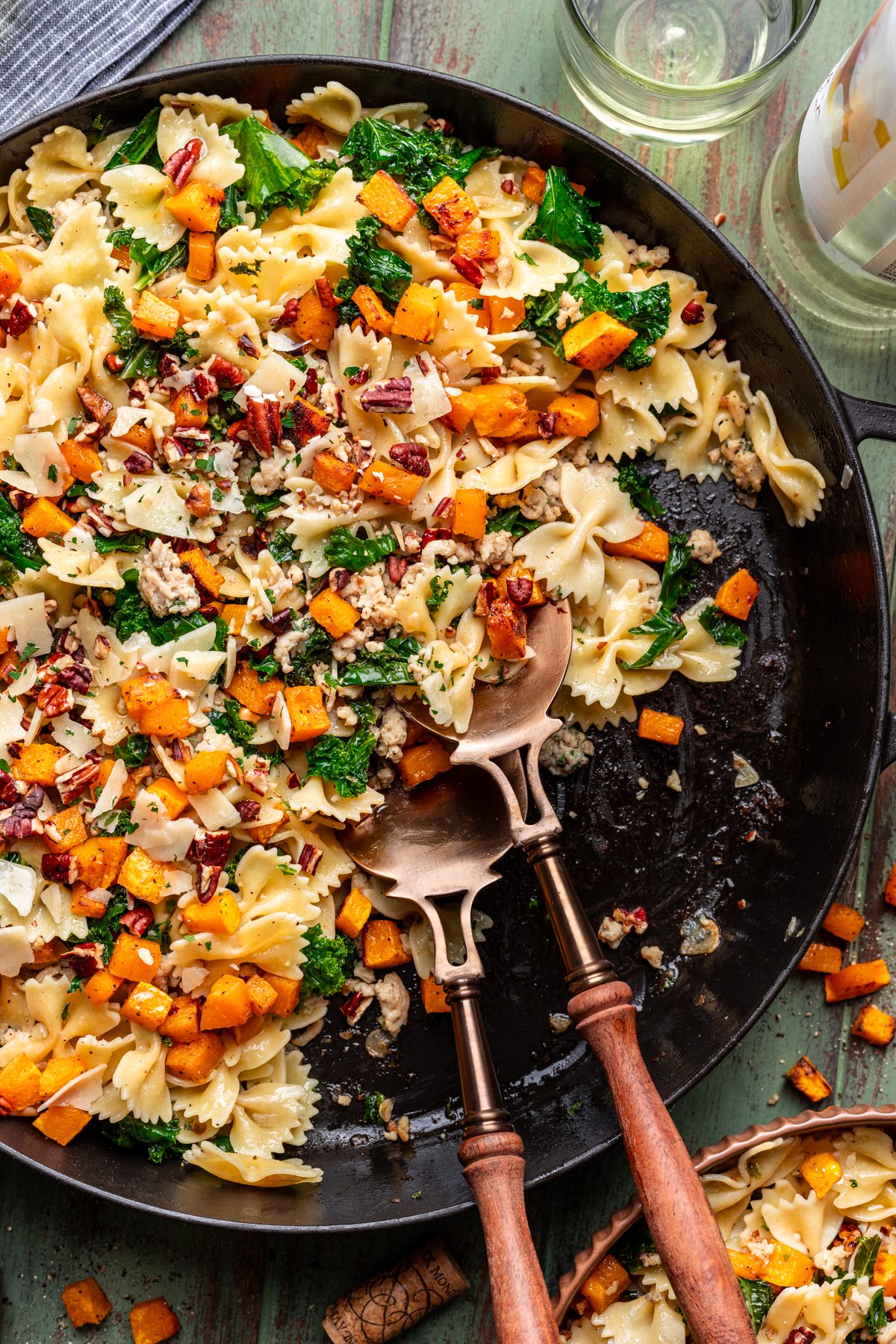 Roasted butternut squash pasta with kale and ground chicken in a large skillet with serving utensils.