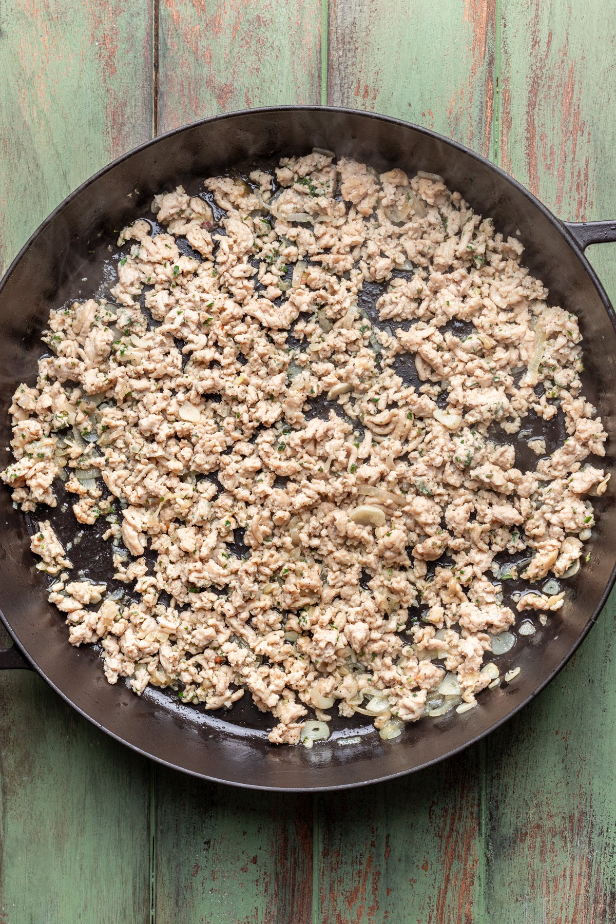 Ground chicken and seasonings added to the skillet.