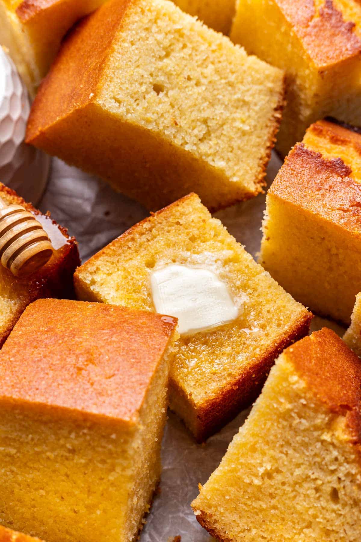A piece of cornbread served with melting butter and a drizzle of honey.
