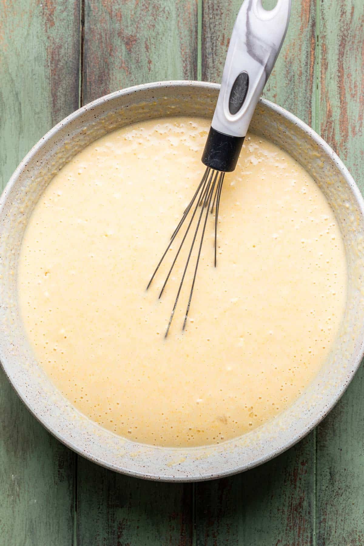 Wet and dry ingredients whisked together in a bowl.