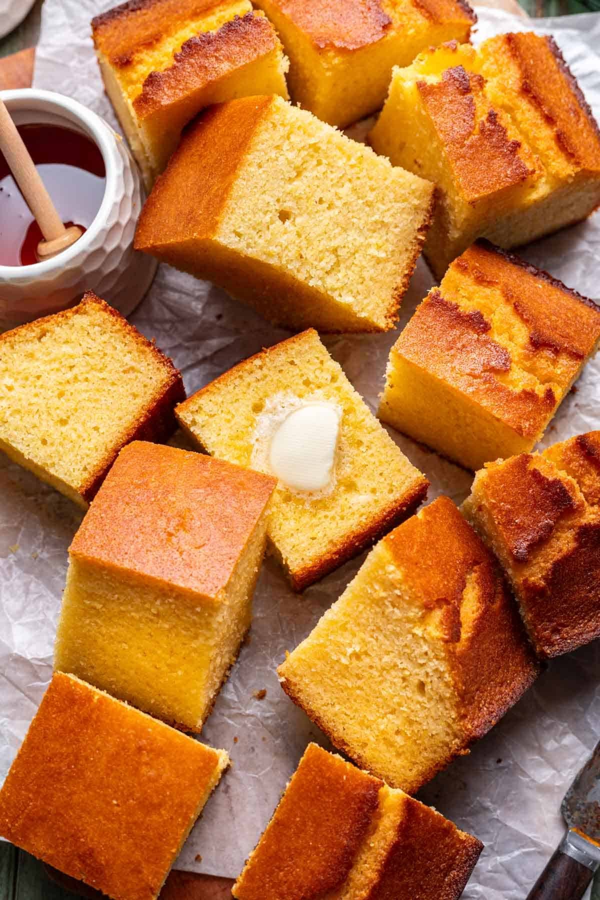 Pieces of cornbread on a serving platter with honey and butter.
