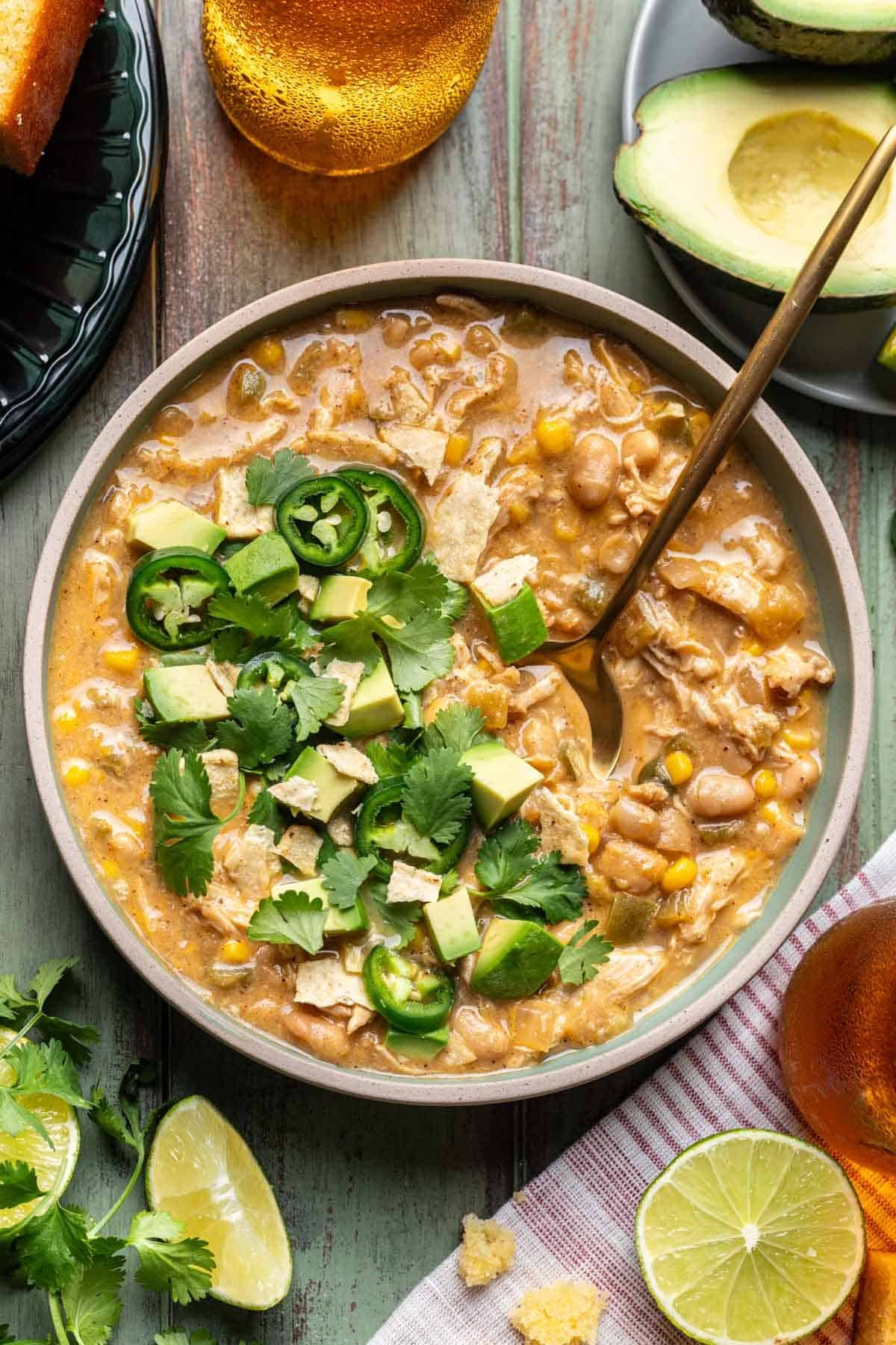 Smoky white chicken chili in a green bowl with a gold spoon.
