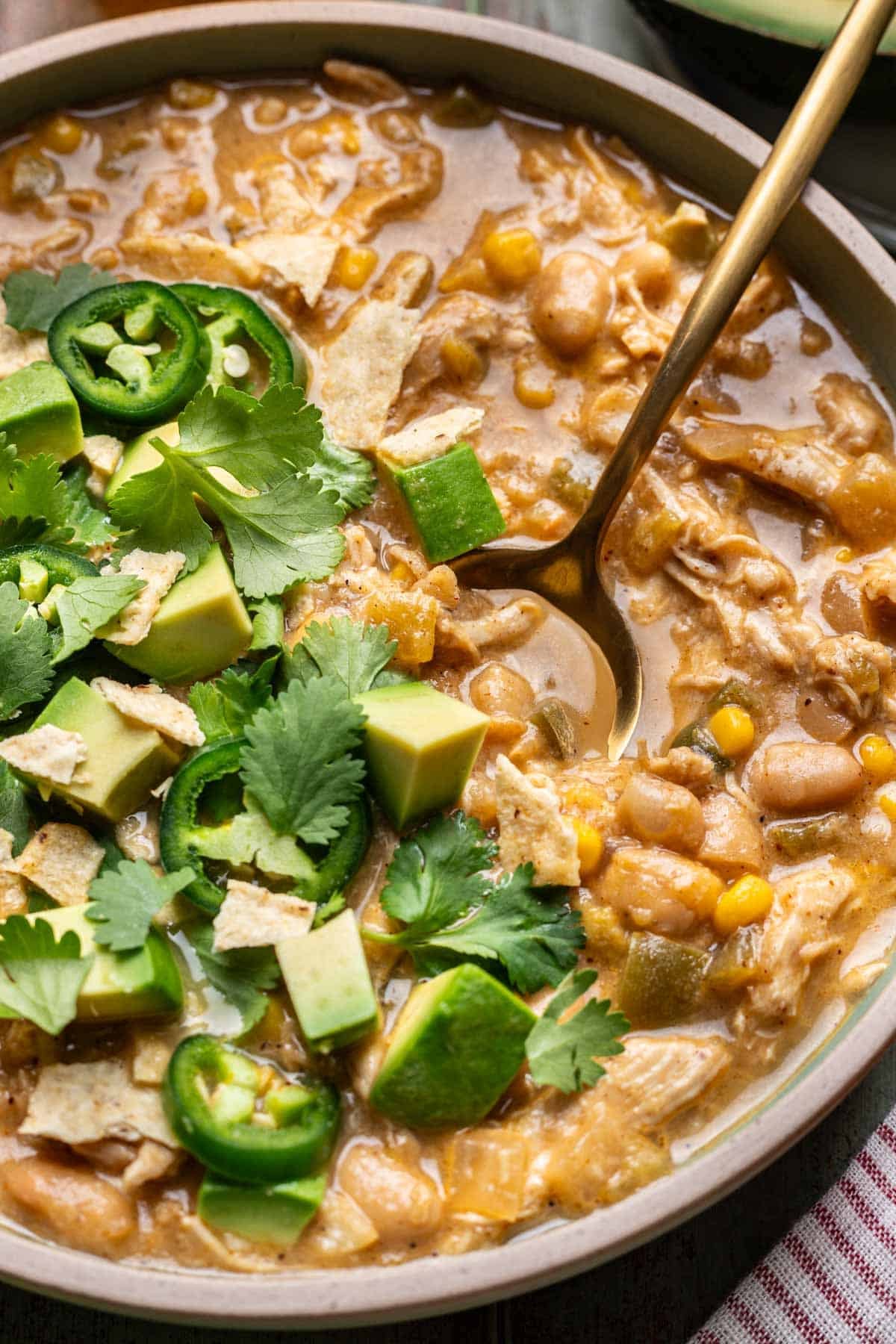 White chicken chili in a bowl with cilantro and diced avocado on top.