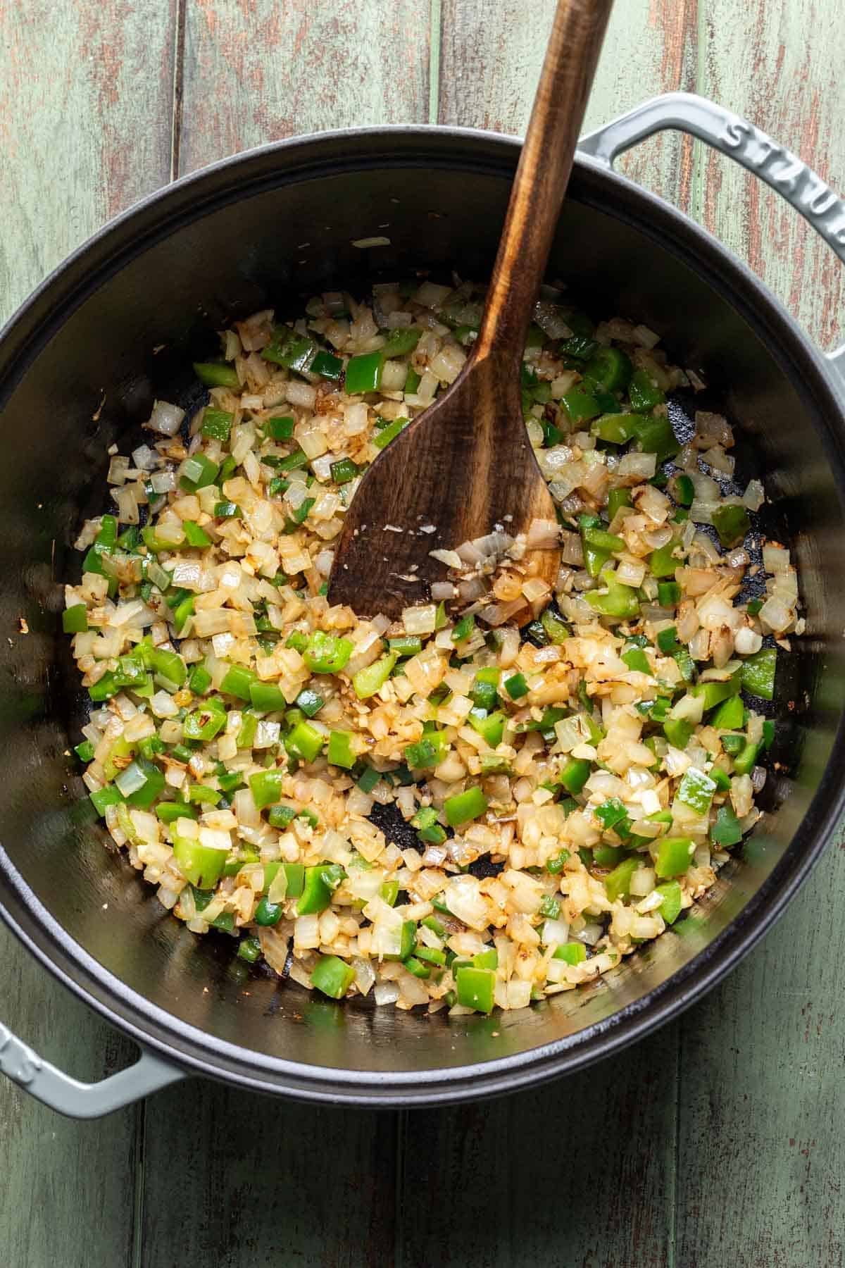 Onion, green pepper, jalapeño, and garlic cooking a large pot.